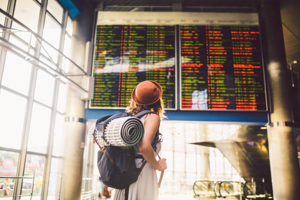 A woman with a backpack looks at an airport departures board